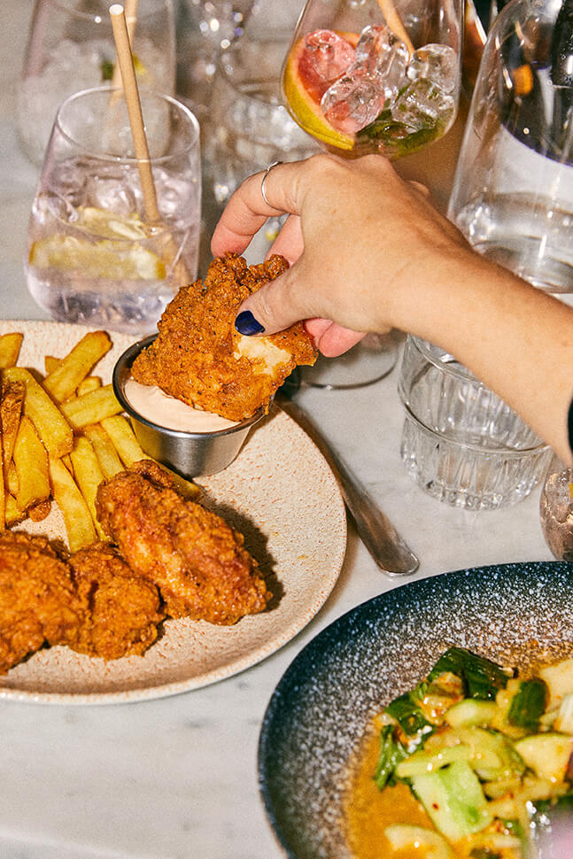 Person dipping fried chicken into sauce