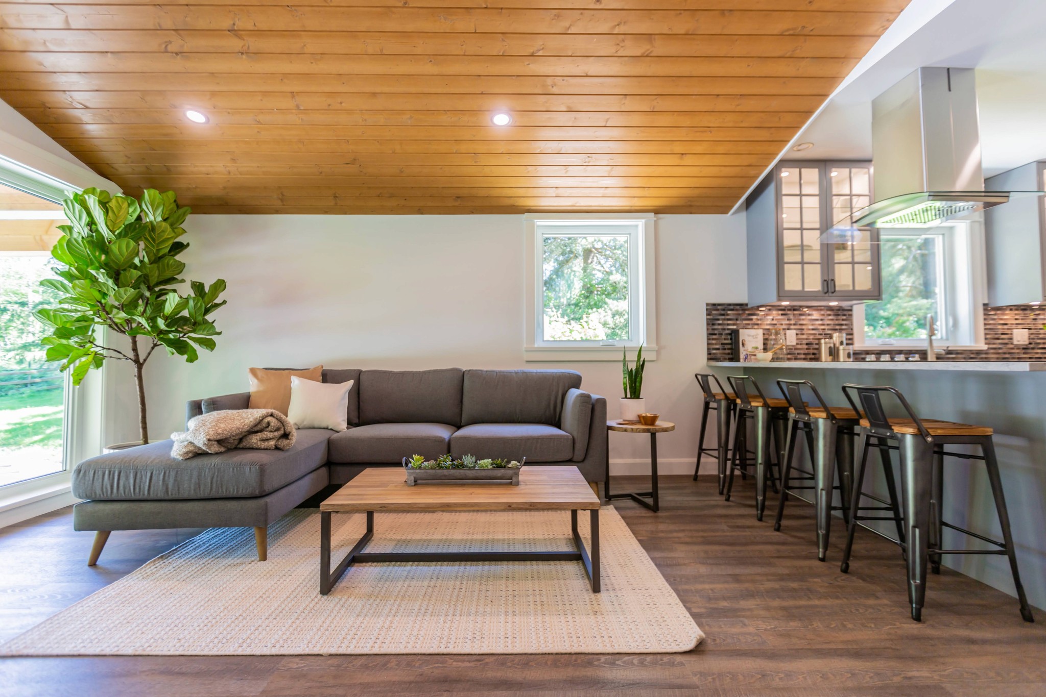 Living room with wood-paneled ceiling and open bar-style seating.