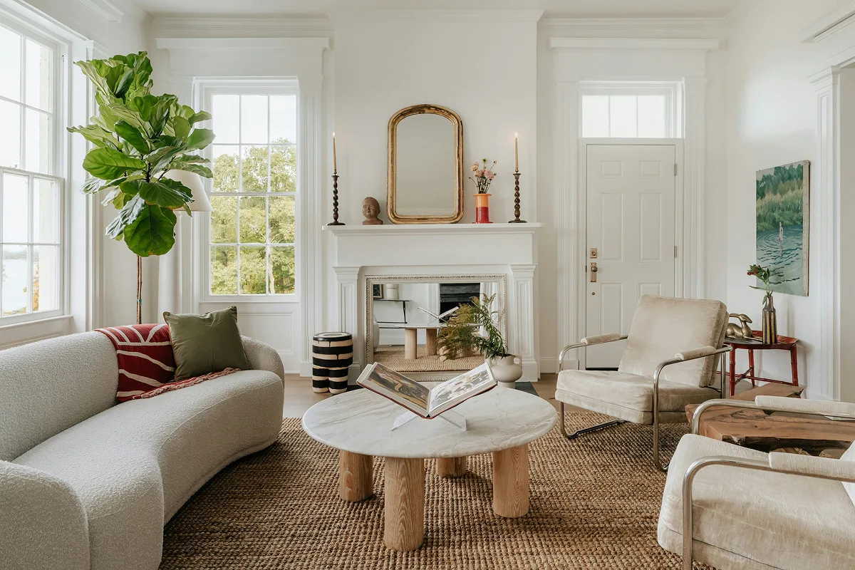 A modern, asymmetrical living room with a cream bouclé sofa, sculptural marble coffee table, and two velvet chairs.
