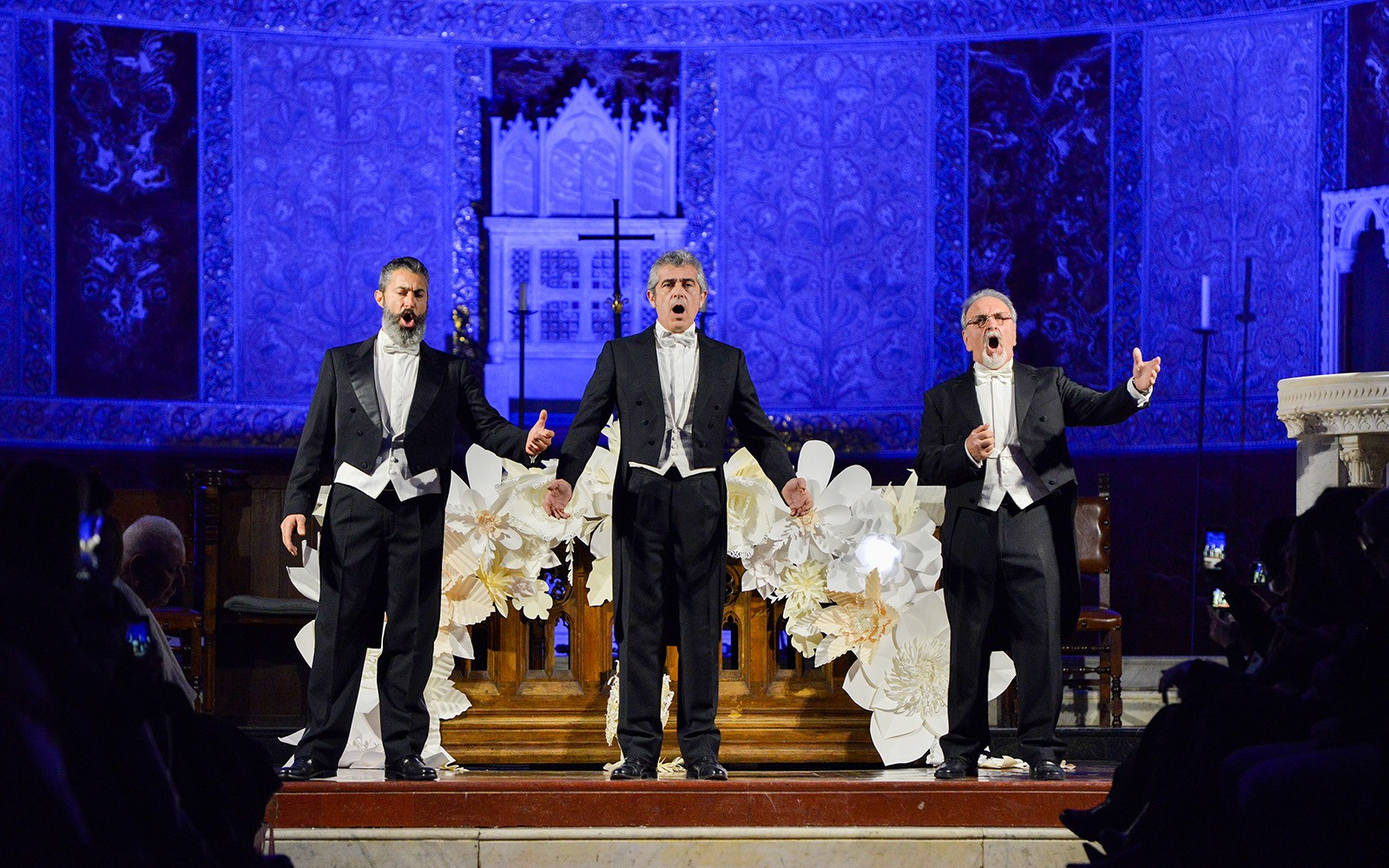 Des chanteurs d'opéra se produisant sur scène lors d'un événement nocturne avec un élégant décor bleu.
