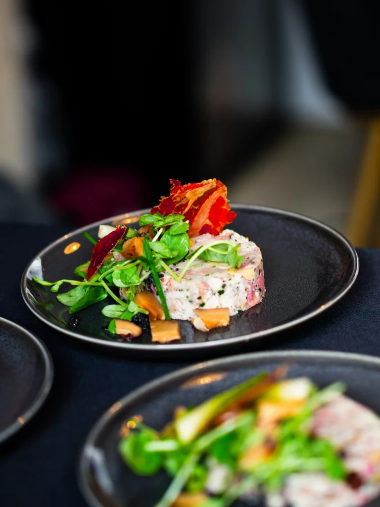 Plated chicken terrine starter with crisp Parma ham and pea shoots