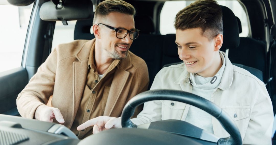 Dad in passenger seat of vehicle, son in drivers seat.