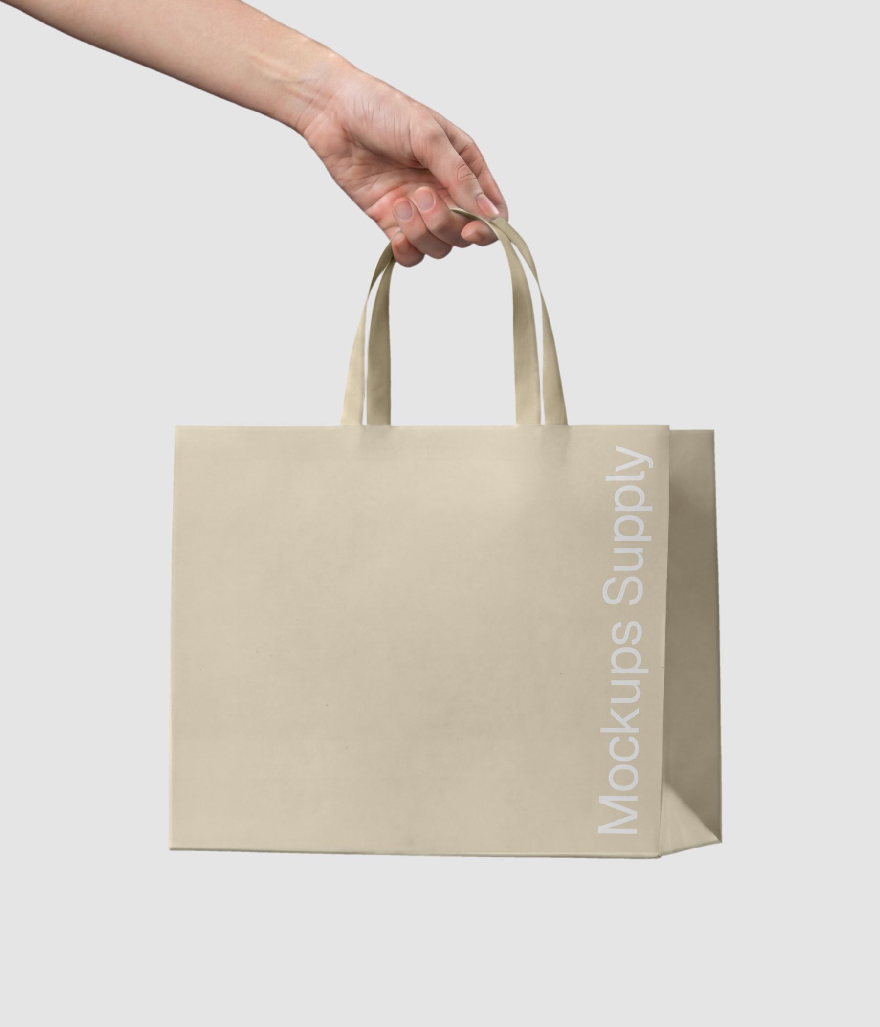 Hand holding paper bag mockup with ribbon handle for luxury brand presentation download on Mockups Supply