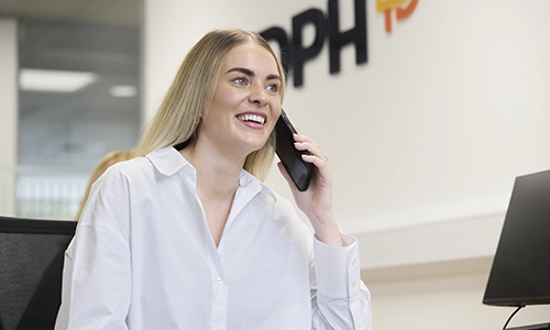 Modern glass building with illuminated facade and trees at sunset