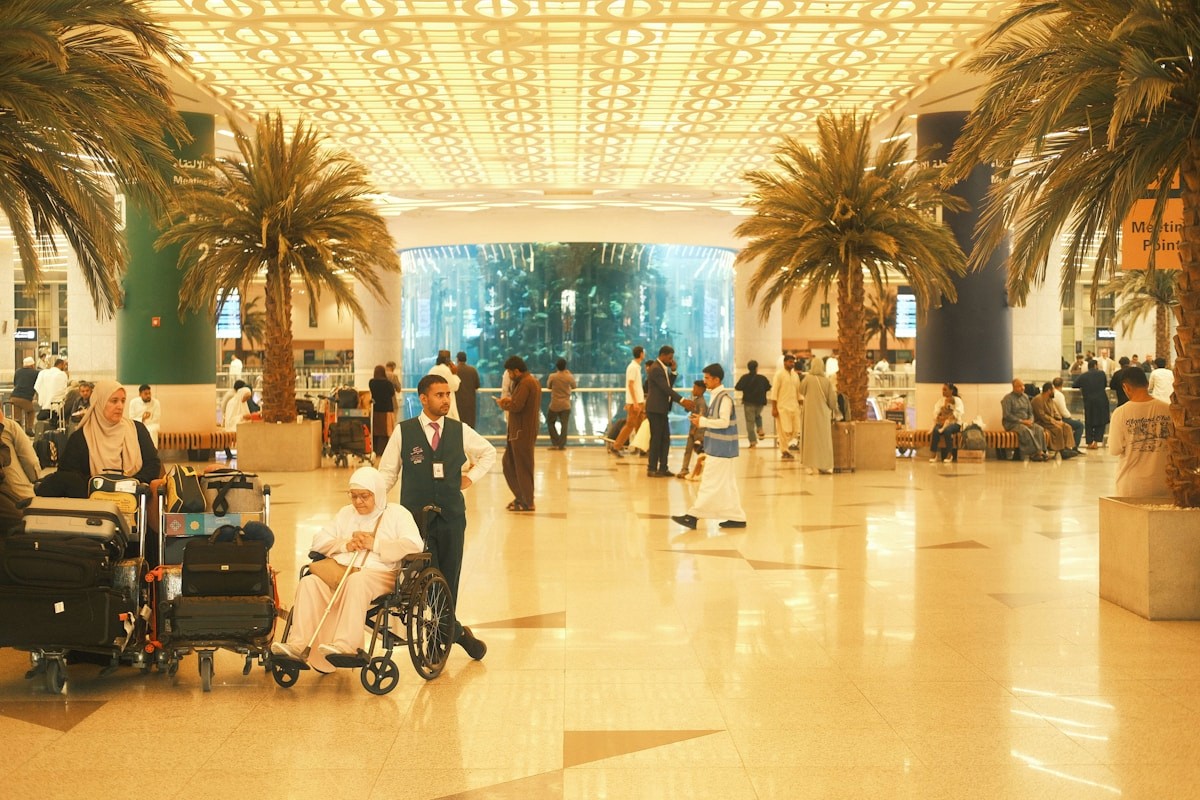 Travelers moving through an airport terminal with palm trees