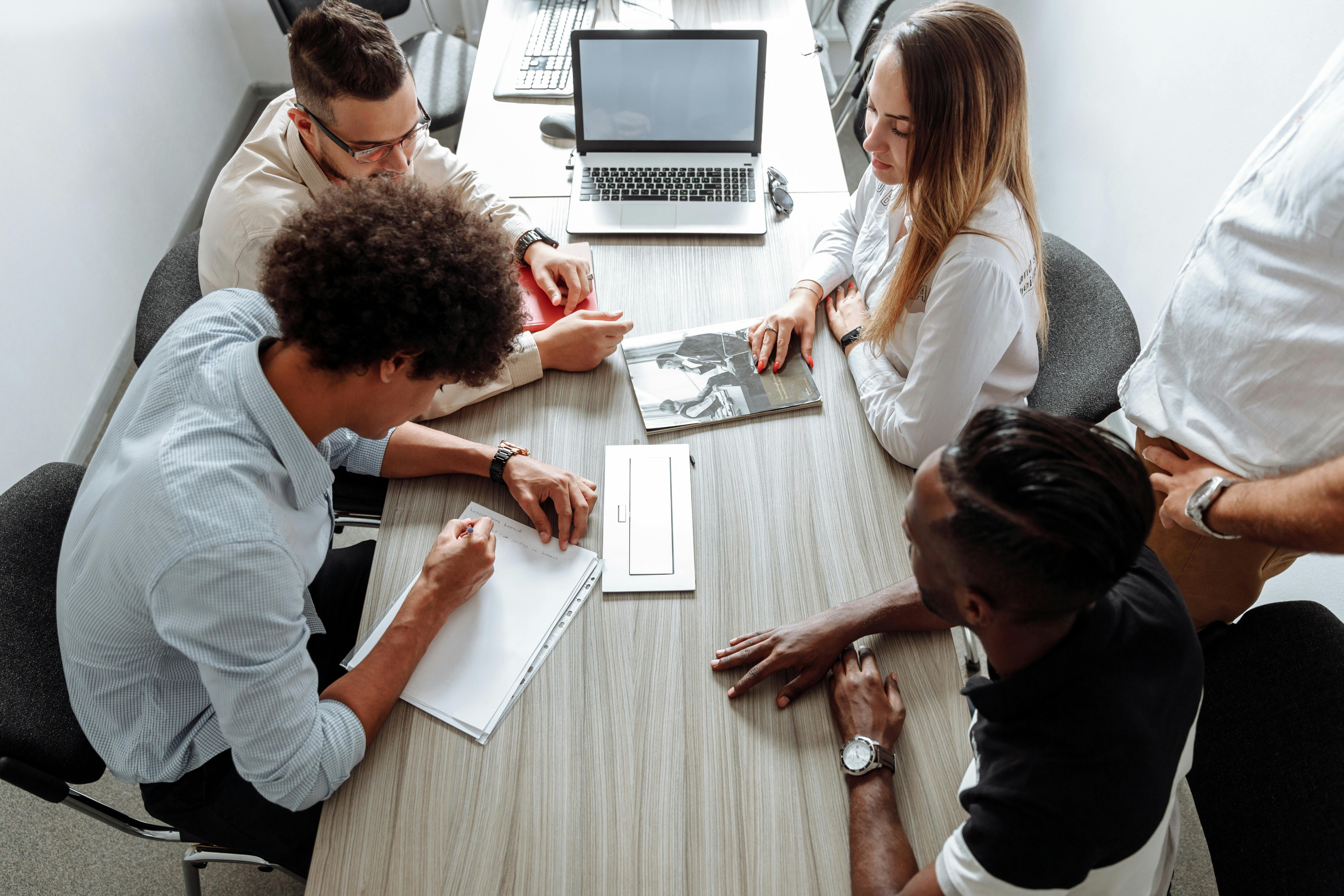 Team riunito attorno al tavolo con laptop: workshop agile e brainstorming su progetto reale