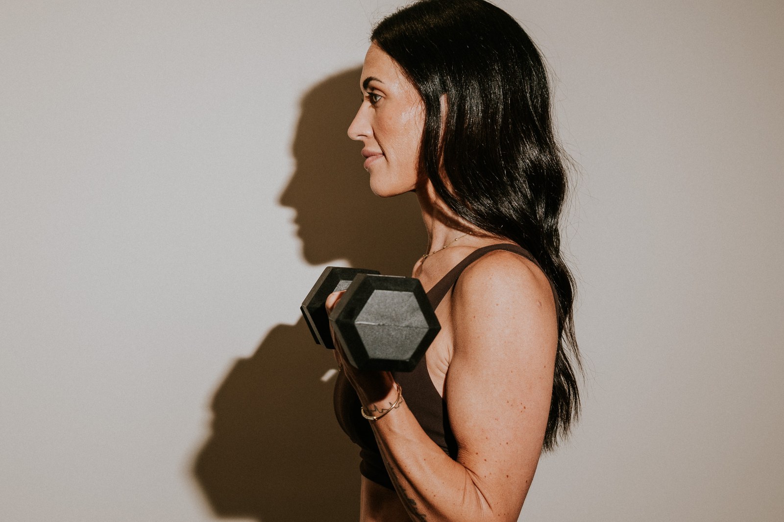 Shae Davis lifting a dumbbell in warm side light.