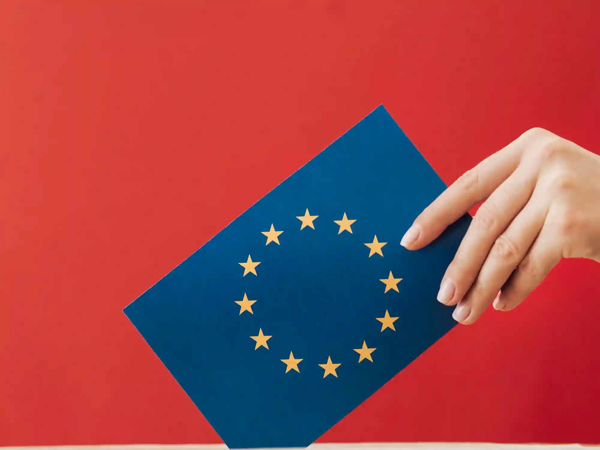 A hand holding the European Union flag against a red background, symbolizing EU regulatory compliance and digital policy.