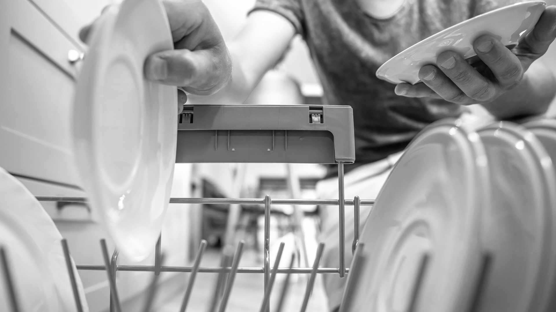 Завантаження тарілок у професійну посудомийну машину для кухні ресторану