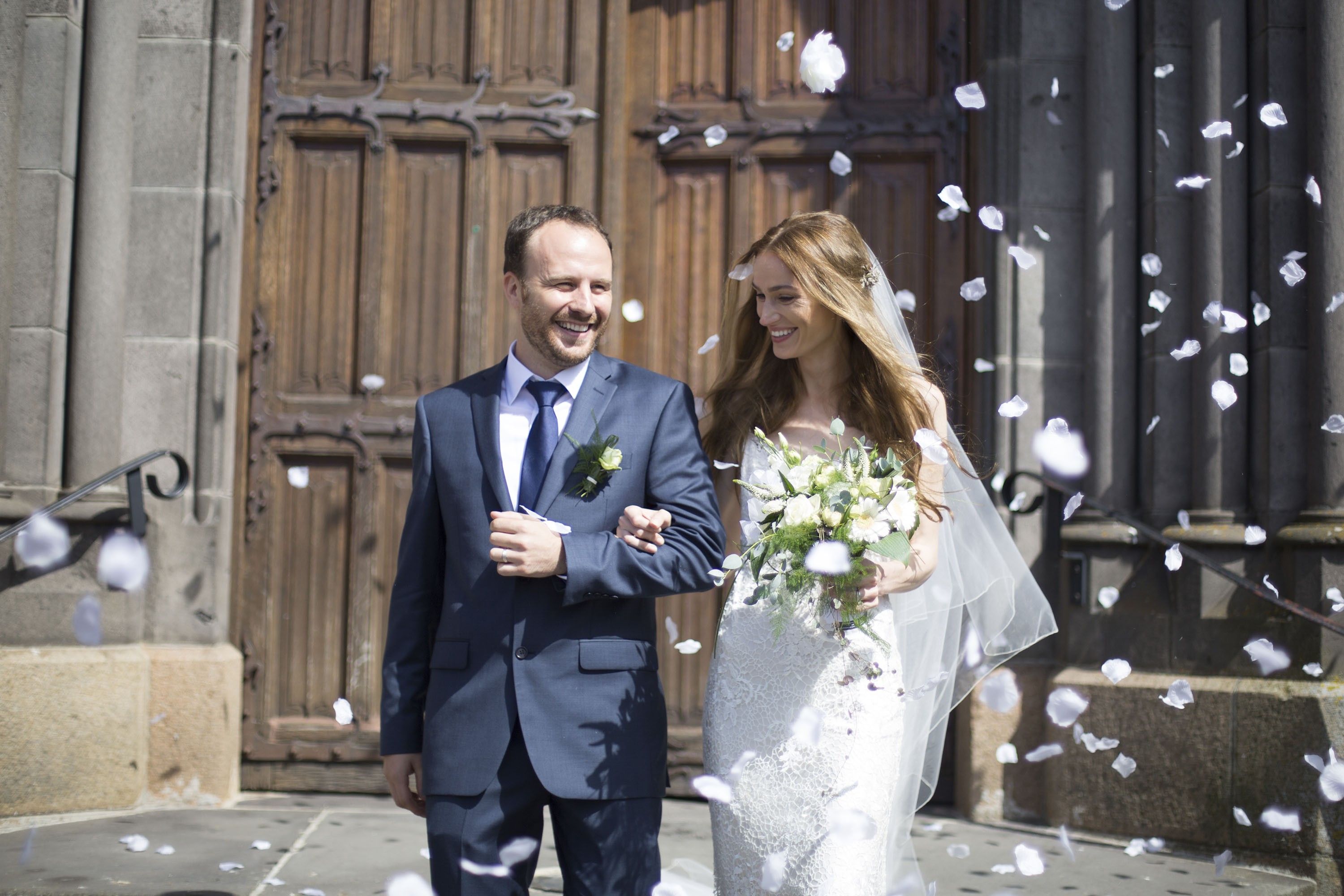 photographe-mariage-la pacaudiere devant l'église une porte en bois un lancée de pétales de rose sur le couple qui s'aime