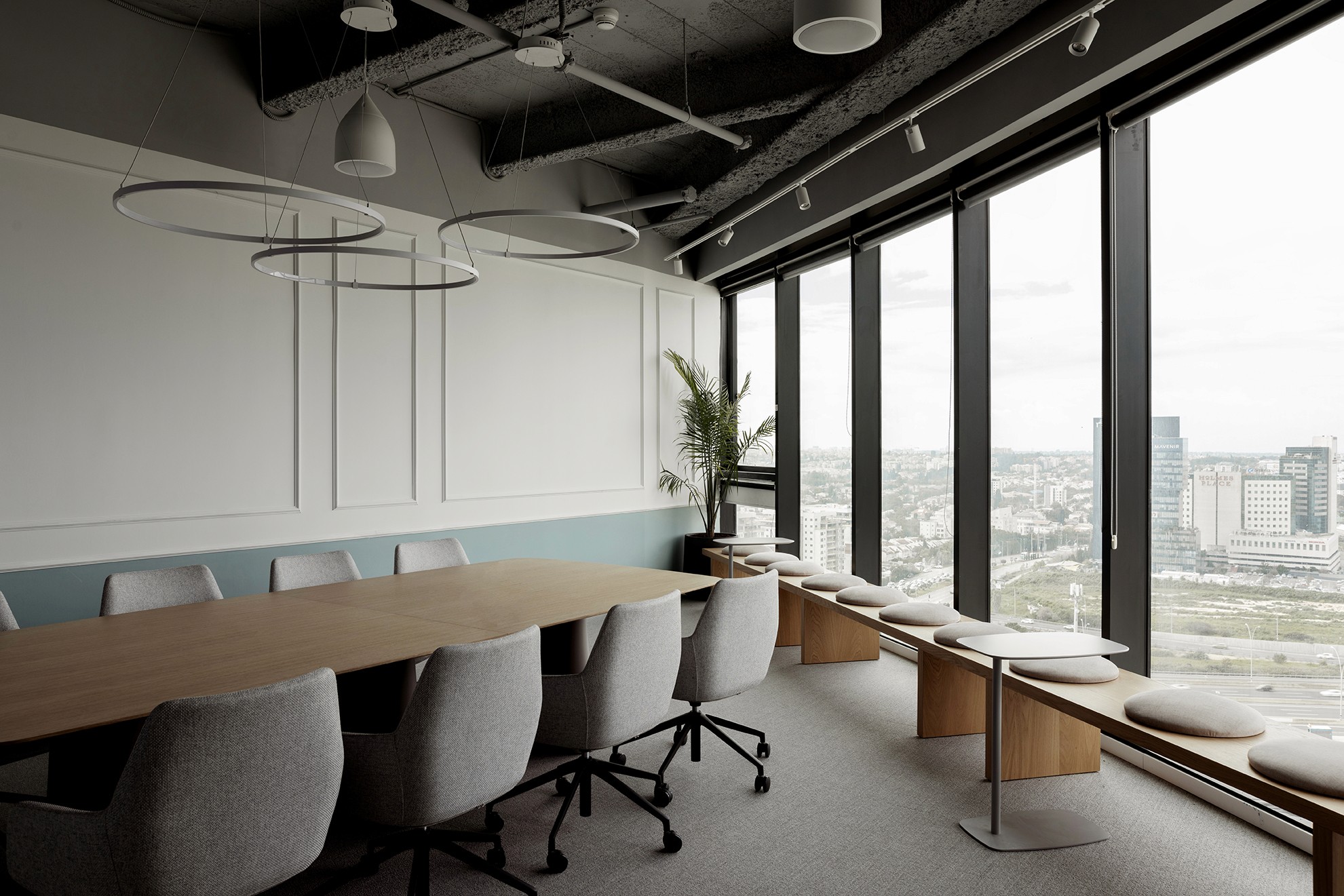 חדר ישיבות פינתי: שולחן עגול לעבודת צוות שיתופית, מוקף מחיצות זכוכית לשקיפות מלאה וחיבור מקסימלי לנוף האורבני