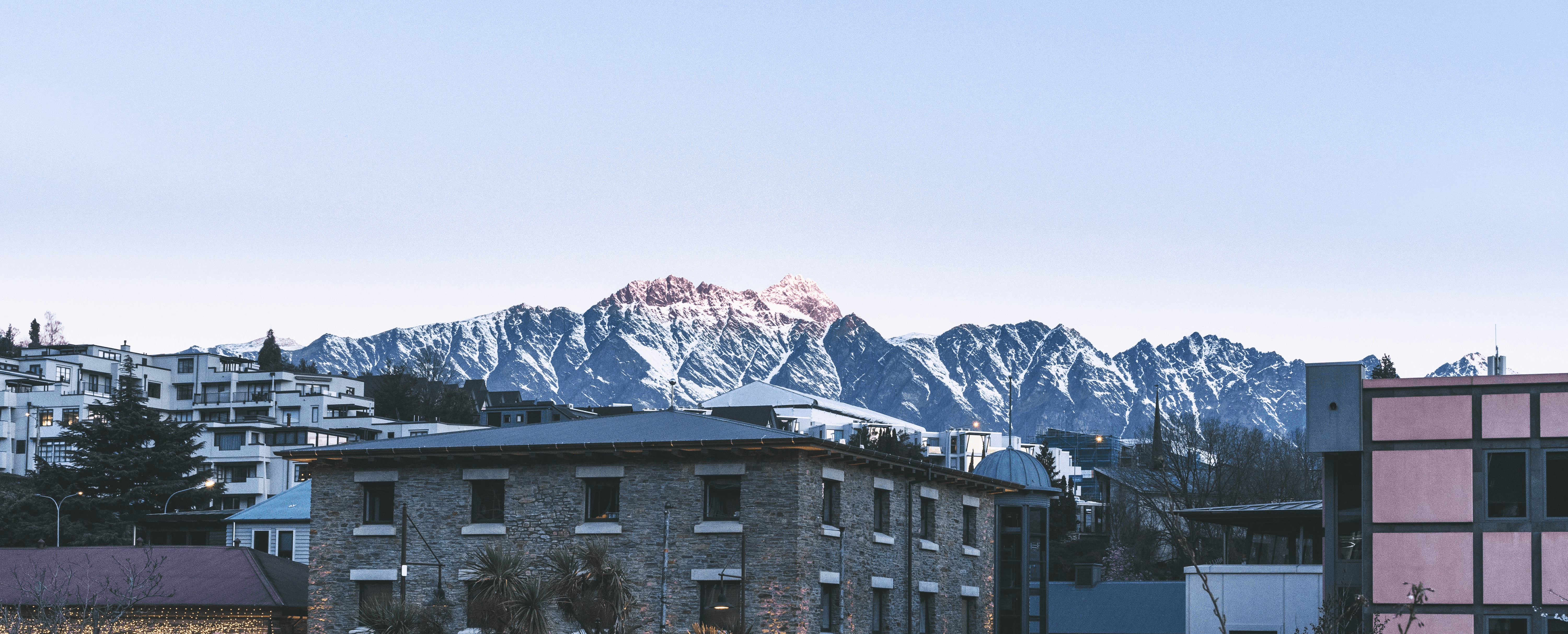 brown and white concrete building near snow covered mountain during daytime