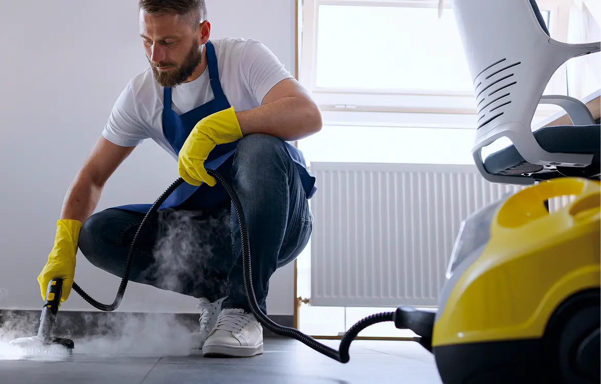 Professionelle Bodenreinigung mit Dampfreiniger durch einen Reinigungsmitarbeiter.