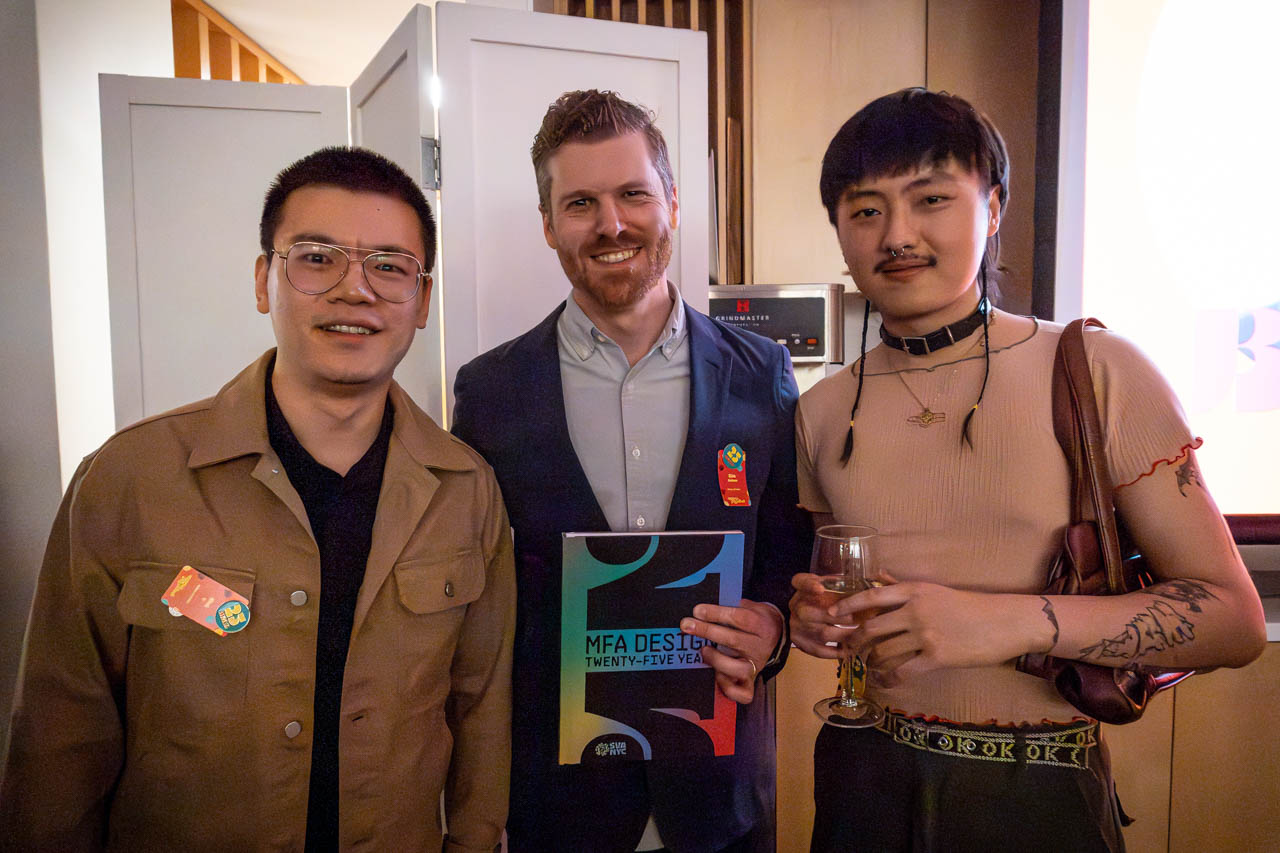three people at cocktail party, one holding a book