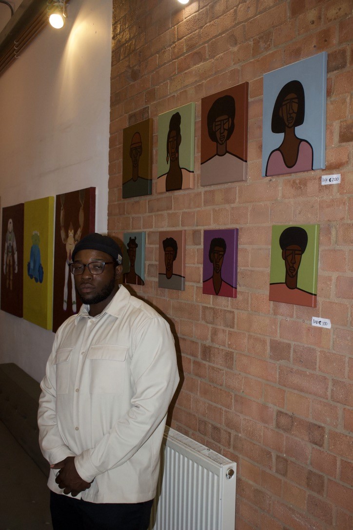 Exhibition visitor beside portraits installed on a brick wall