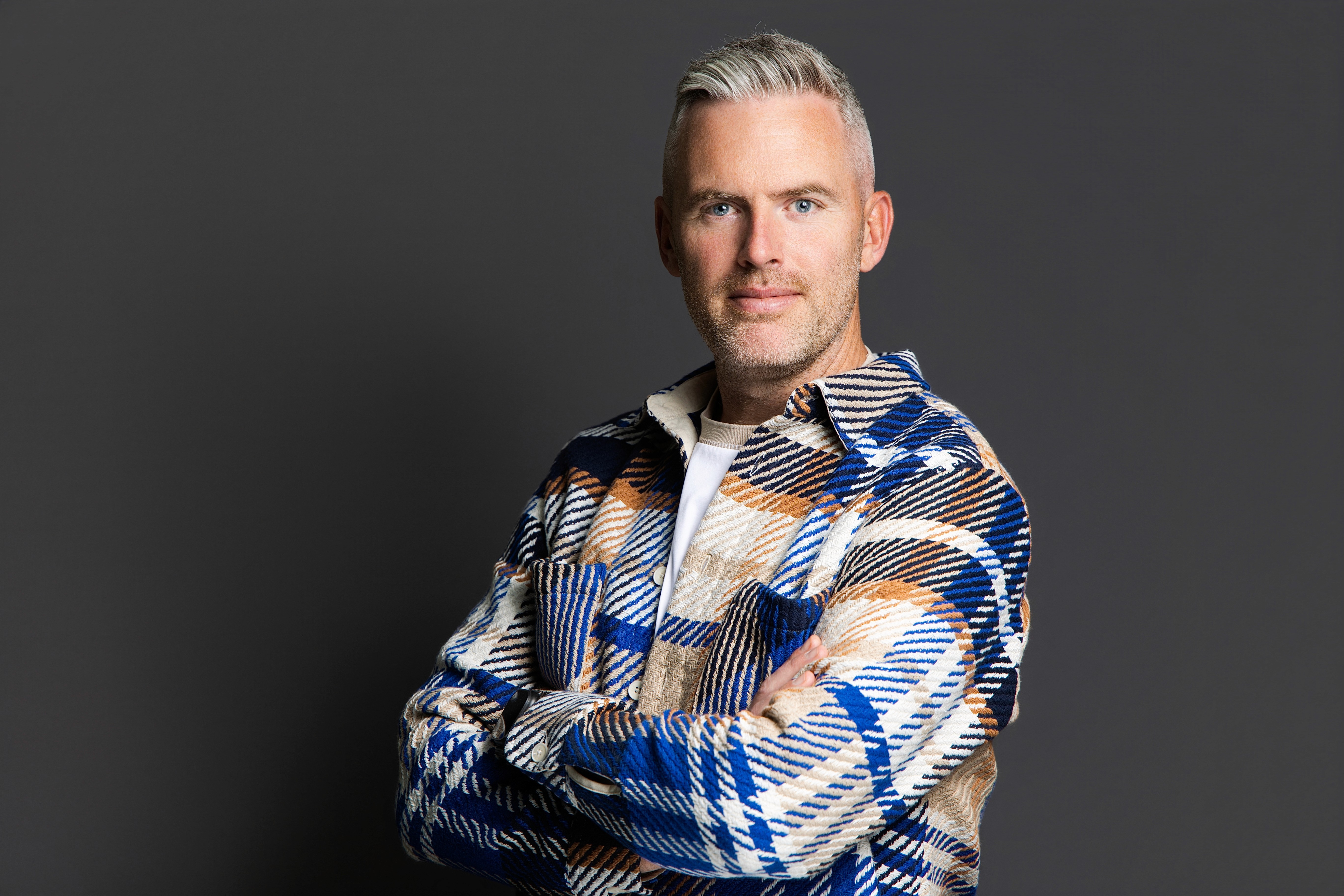 A woman with short curly hair wearing a black t-shirt looks into the camera.