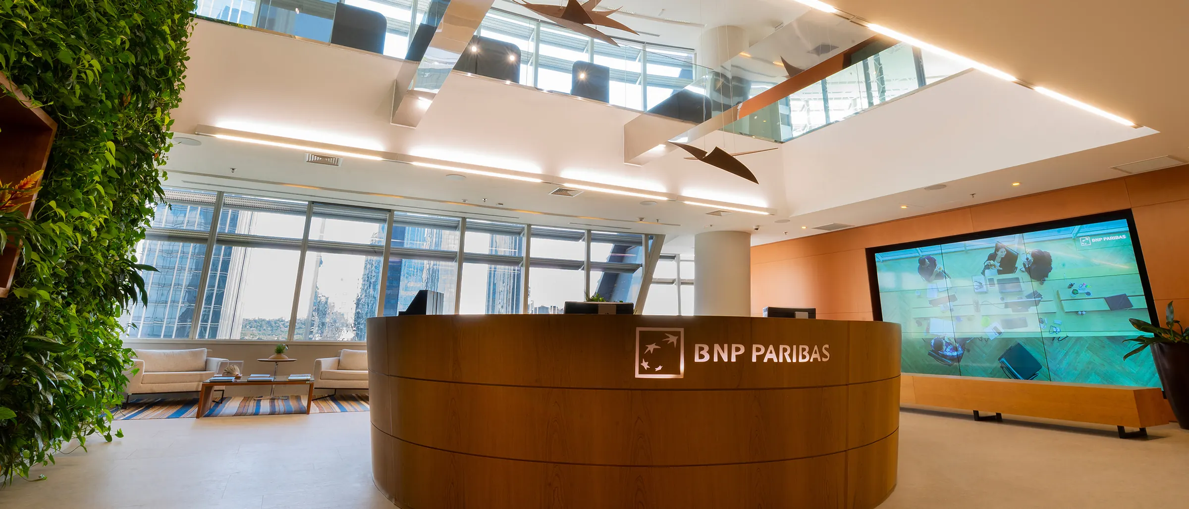 Recepção do escritório do BNP Paribas em São Paulo, com jardim vertical e o logo no balcão