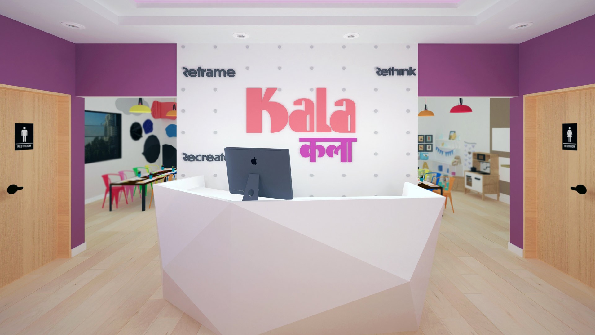 A white, angular reception desk with a dark gray computer monitor sits in a room with light wood flooring and purple walls. The wall behind the desk features the text "Kala" in large pink letters, with smaller text below in pink and purple. A white dotted pattern is visible on the wall behind the desk. Open doorways on either side of the desk lead to other areas with colorful furniture and artwork, including a wall-mounted display of colorful circular shapes.