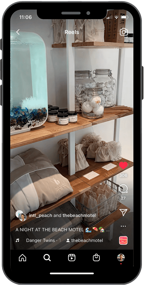 A smartphone screen displaying an Instagram Reel featuring neatly arranged shelves in a boutique motel shop. Items include branded robes, spa products in glass jars, and canvas drawstring bags, creating a clean, coastal aesthetic.