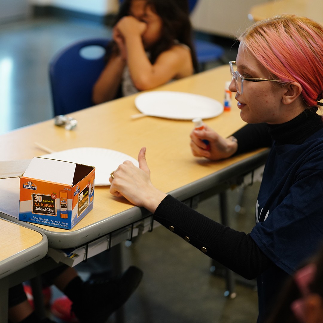 nstructor demonstrating step-by-step craft activity during school enrichment program