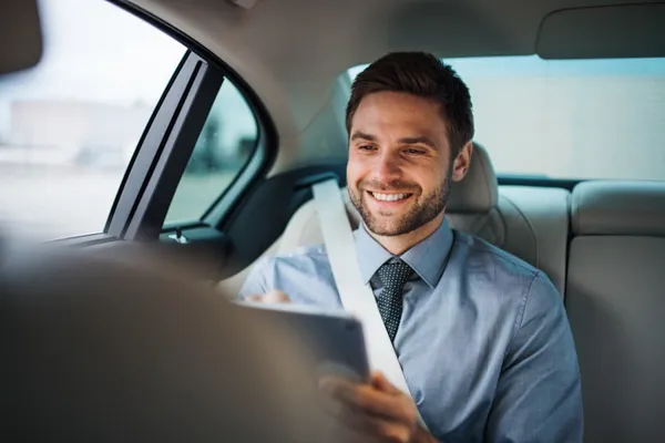 Homem sorridente no banco traseiro de carro — transferes empresariais · Táxi Afonso · 06 Caminha
