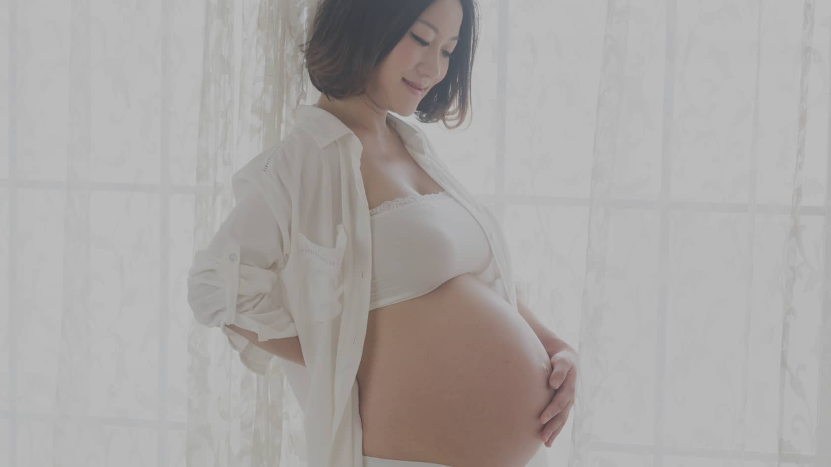 Image douce d'une future maman épanouie regardant son ventre avec amour. Cette image illustre notre article de blog FitMum France détaillant les mouvements à éviter enceinte et comment s'entraîner en toute sécurité grâce à des alternatives sportives prénatales adaptées.
