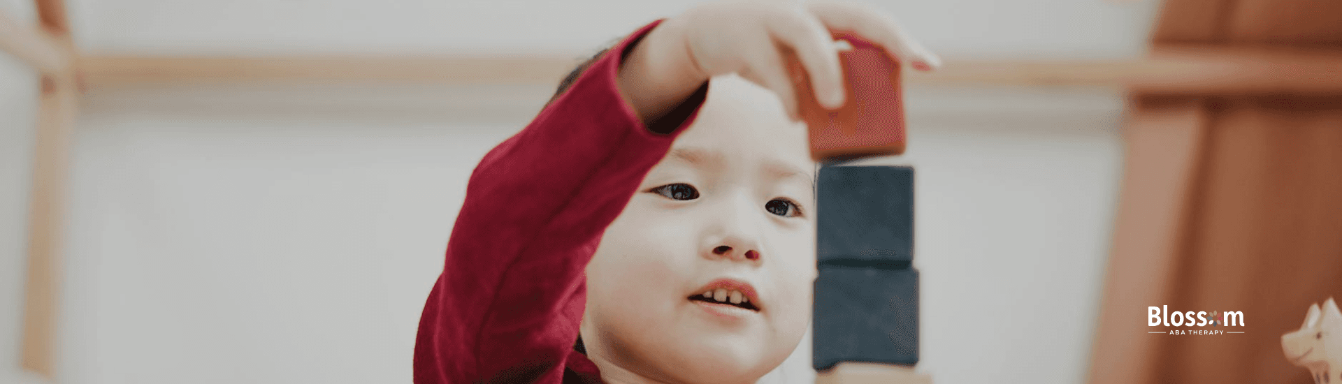 Autistic toddler stacking colorful wooden blocks, concentrating on ABA therapy in Tennessee.