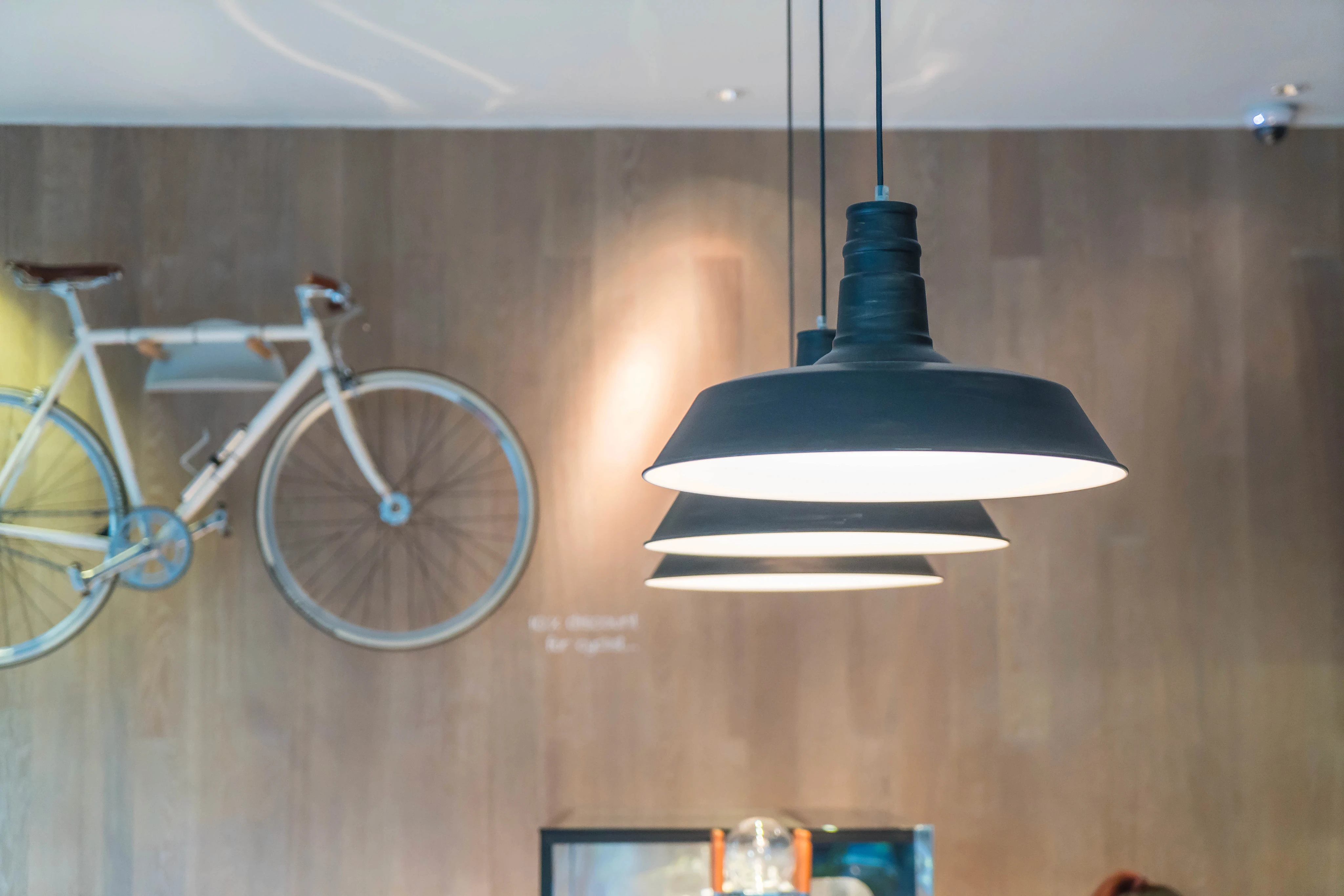 Industrial interior decor featuring pendant lights suspended in front of a wall-mounted bicycle.