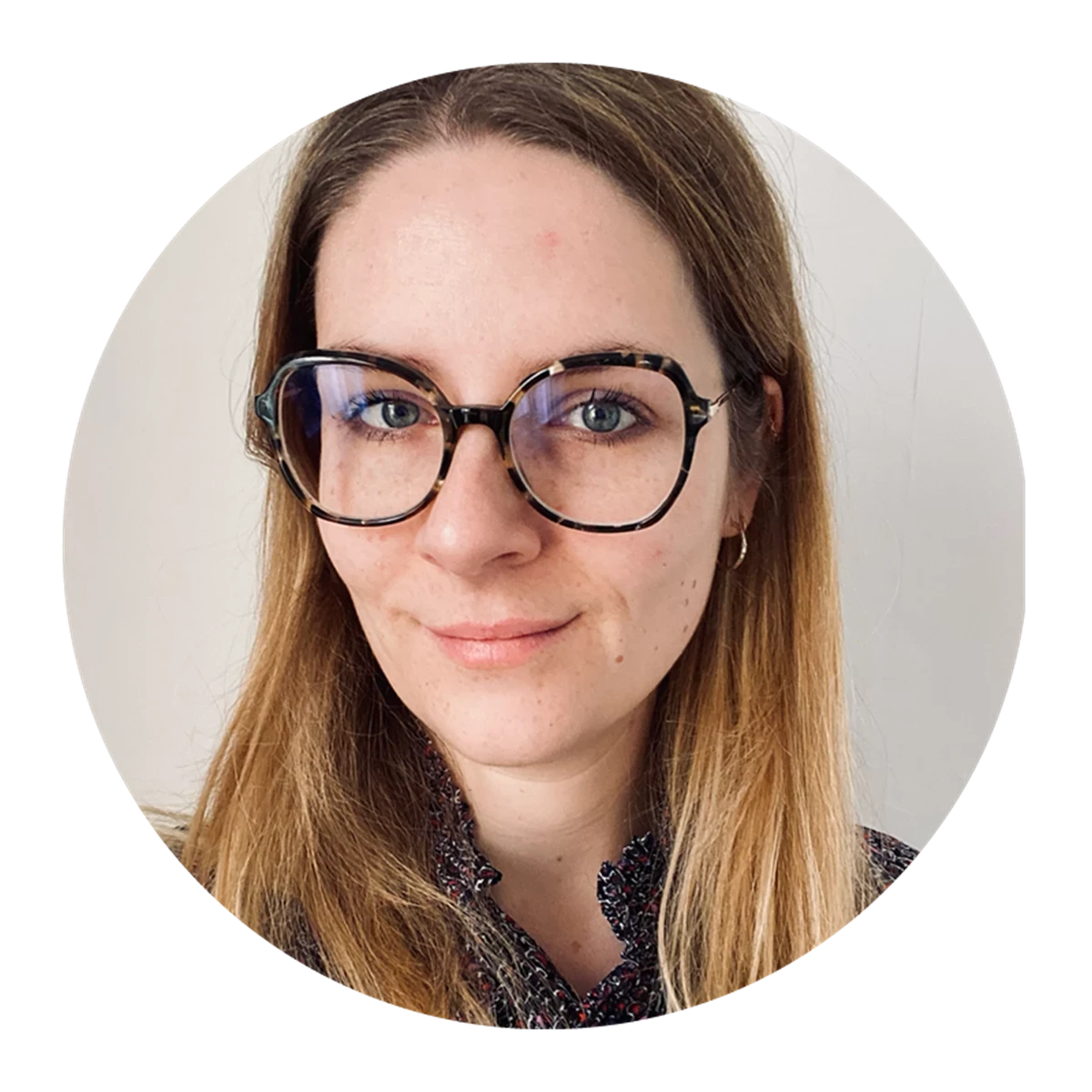 Person with straight light brown hair wearing glasses and a patterned top.