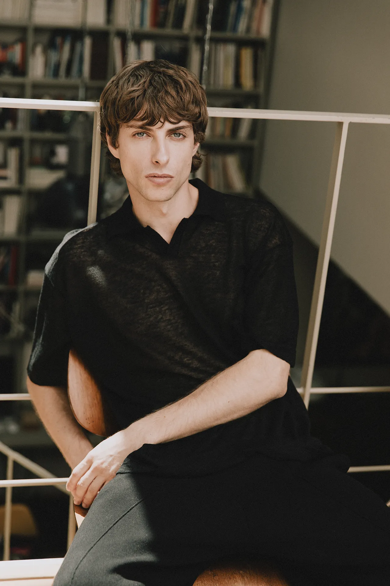 Close-up of Annapurna SS26 collection men's black semi-sheer knit polo shirt with a V-neck collar.