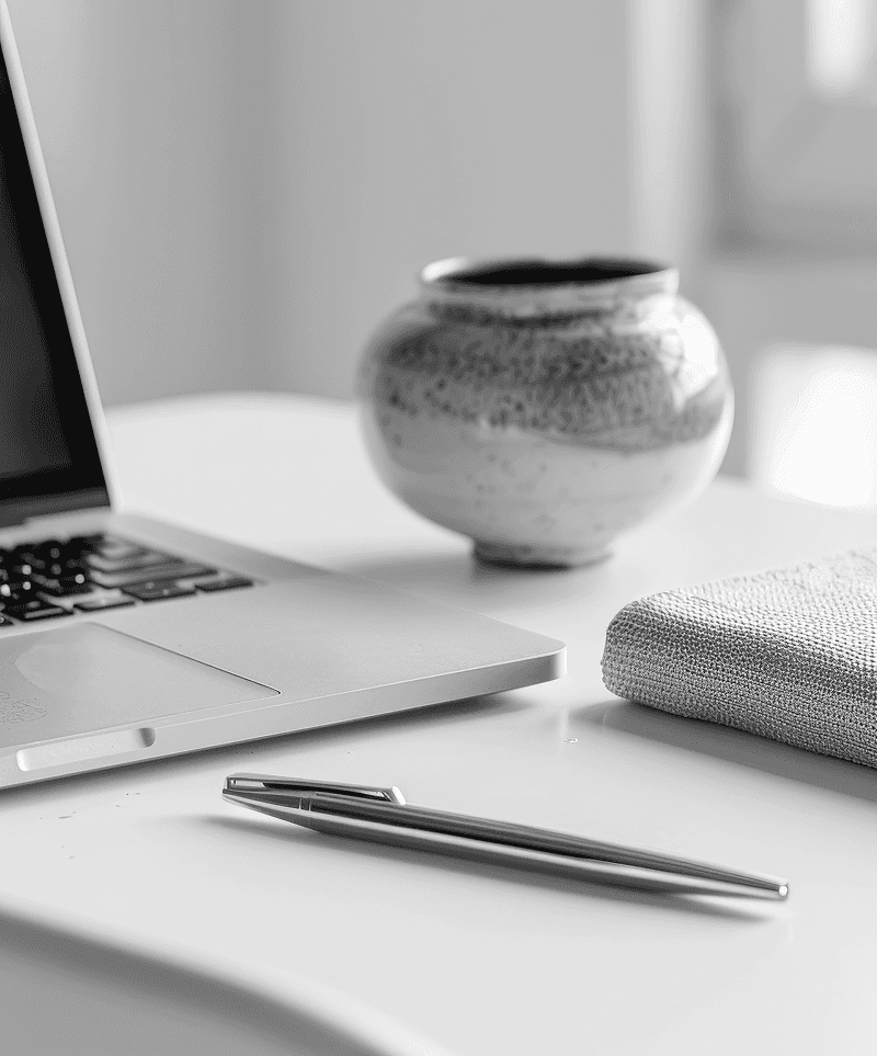 Laptop, pen, and legal book on a desk, representing professional notarial services.