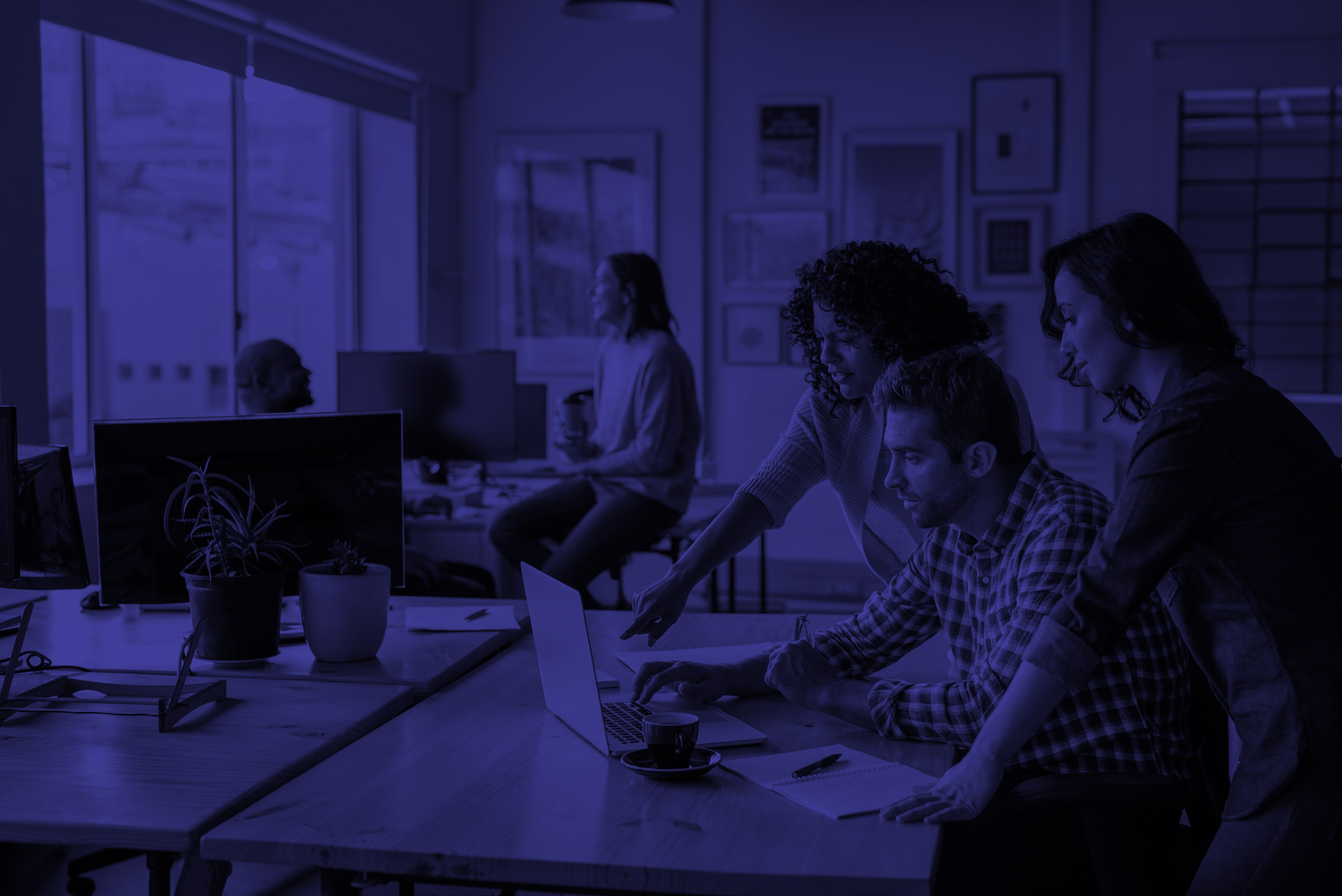  Collaborative work session overhead view of six people collaborating at a rustic wooden table with coffee, papers, and a laptop