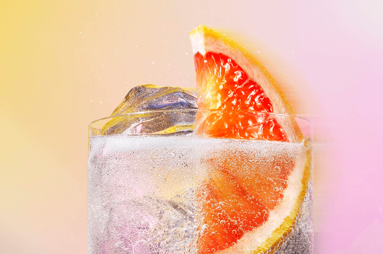 Refreshing citrus cocktail with ice cubes, grapefruit slice, and fizzy bubbles.