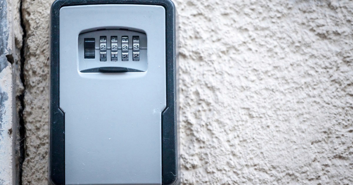 A close-up of a lock box mounted to the side of a building. There is a combination of numbers that opens the box.