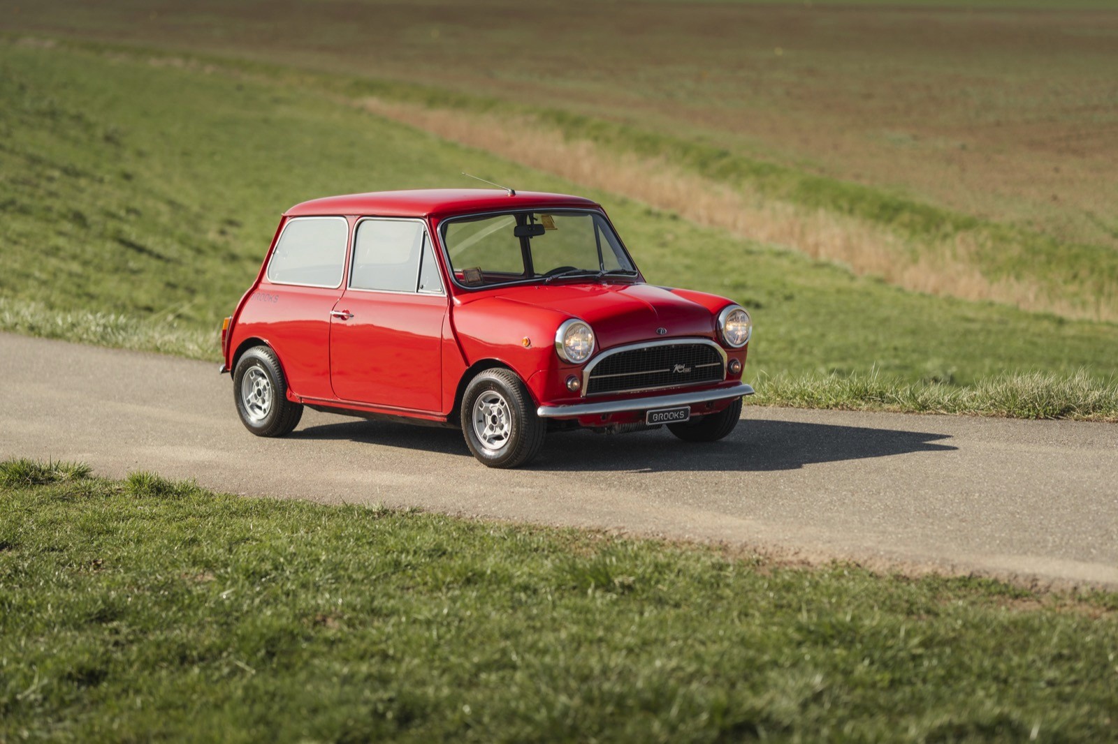 Red classic Mini car on a scenic road.