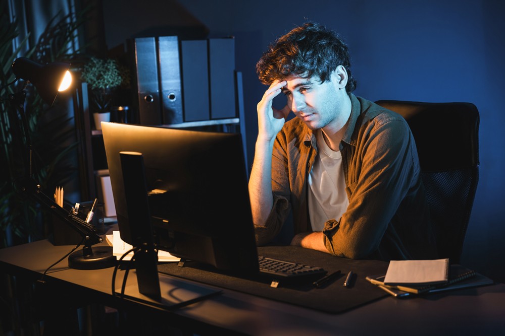 A man seating infront of a computer confused as his developer burned him without any result