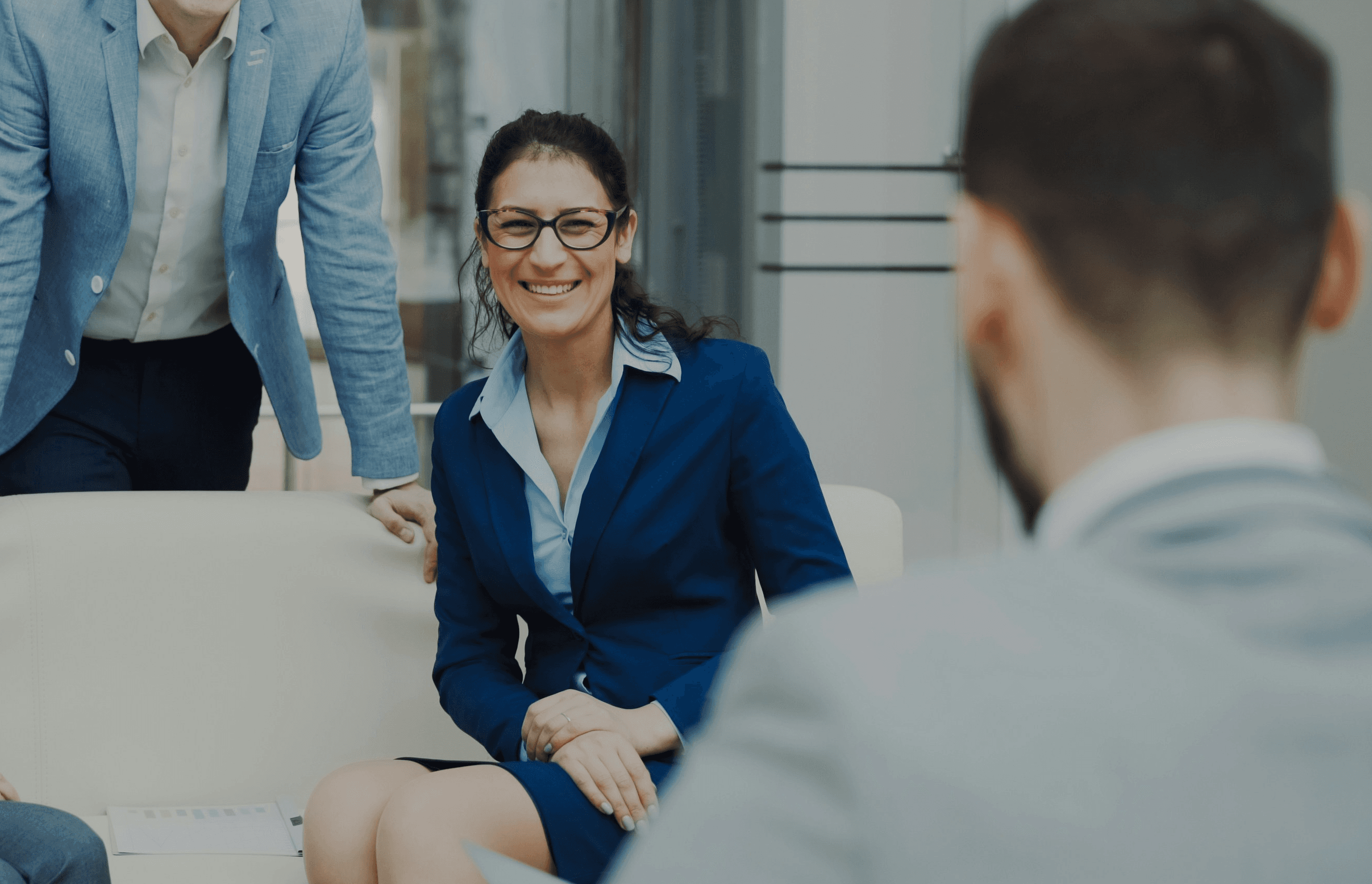 Four smiling business people in a modern office.