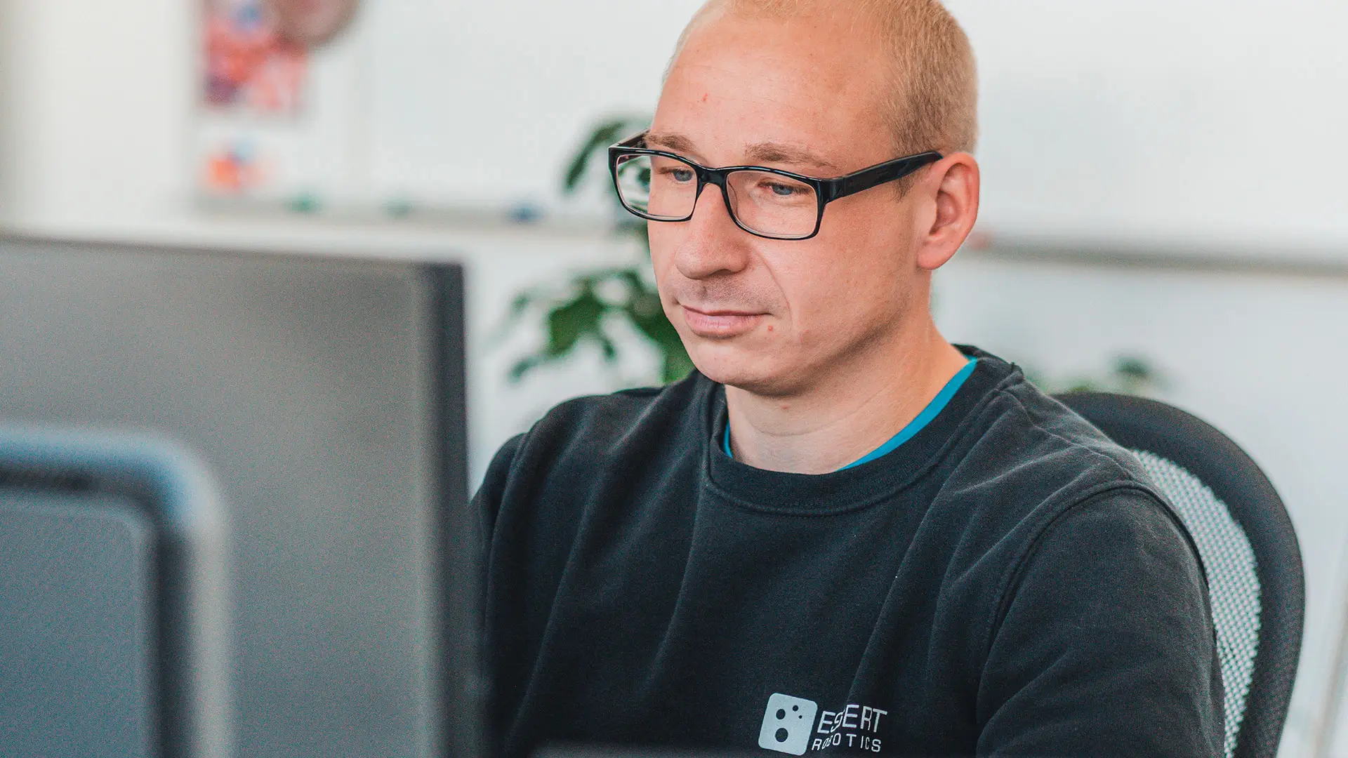 Man with glasses looking at a monitor