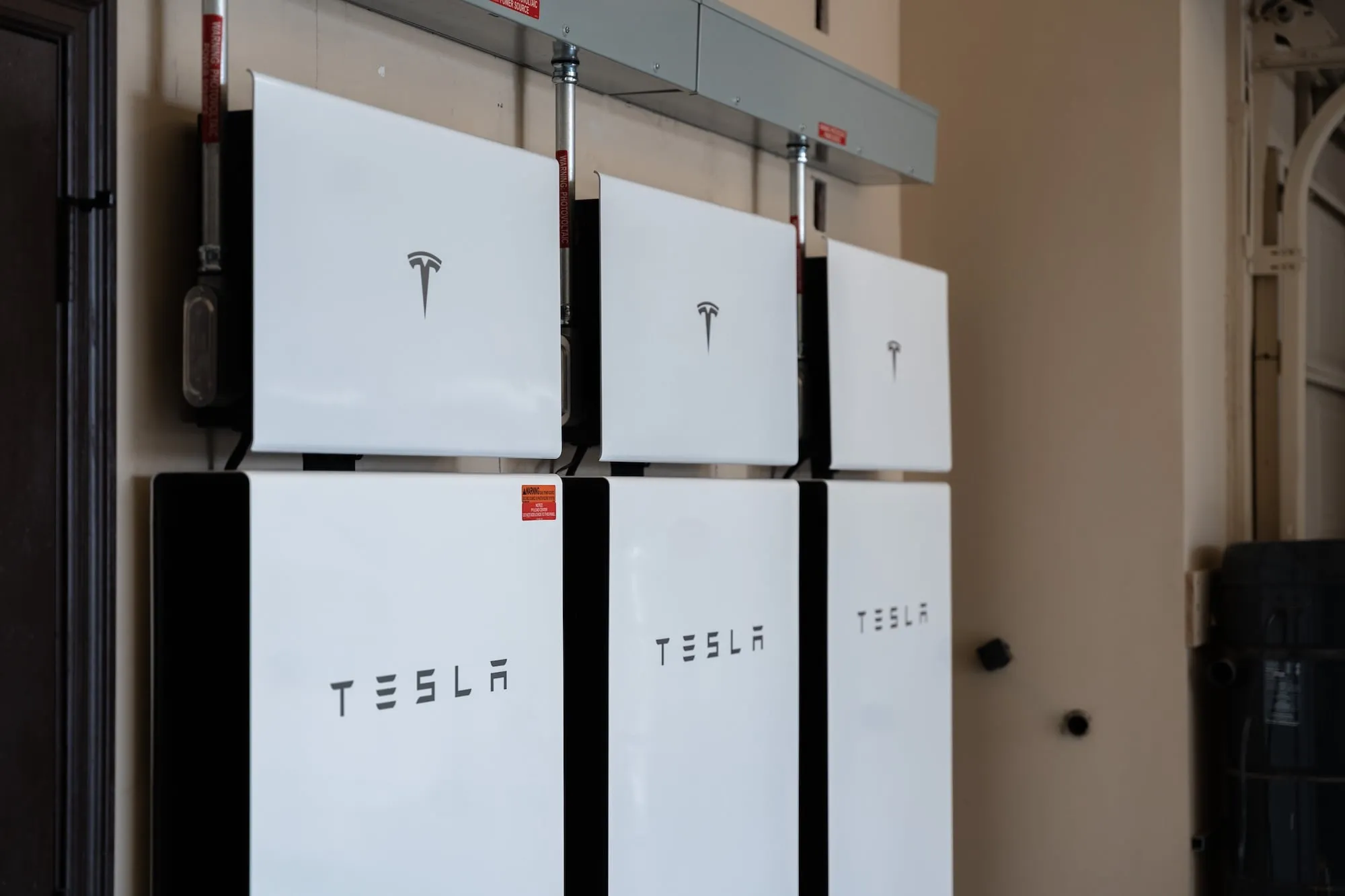 Three Tesla Powerwall batteries mounted side by side on an interior wall