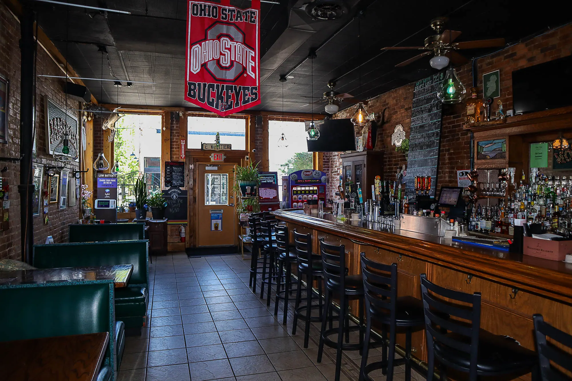 Long wooden bar and green booths inside Hey Hey Bar & Grill