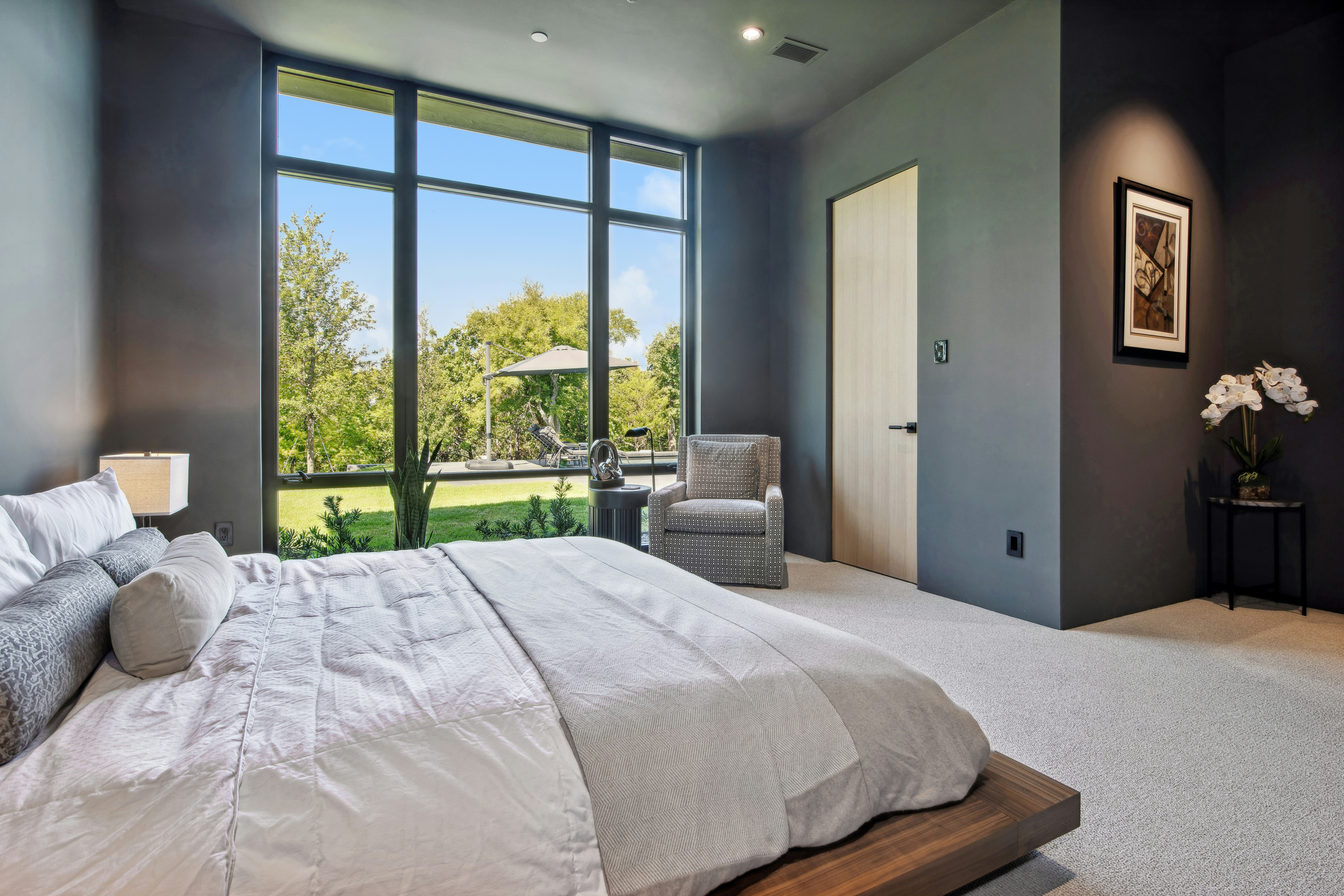 Modern bedroom with large window overlooking greenery