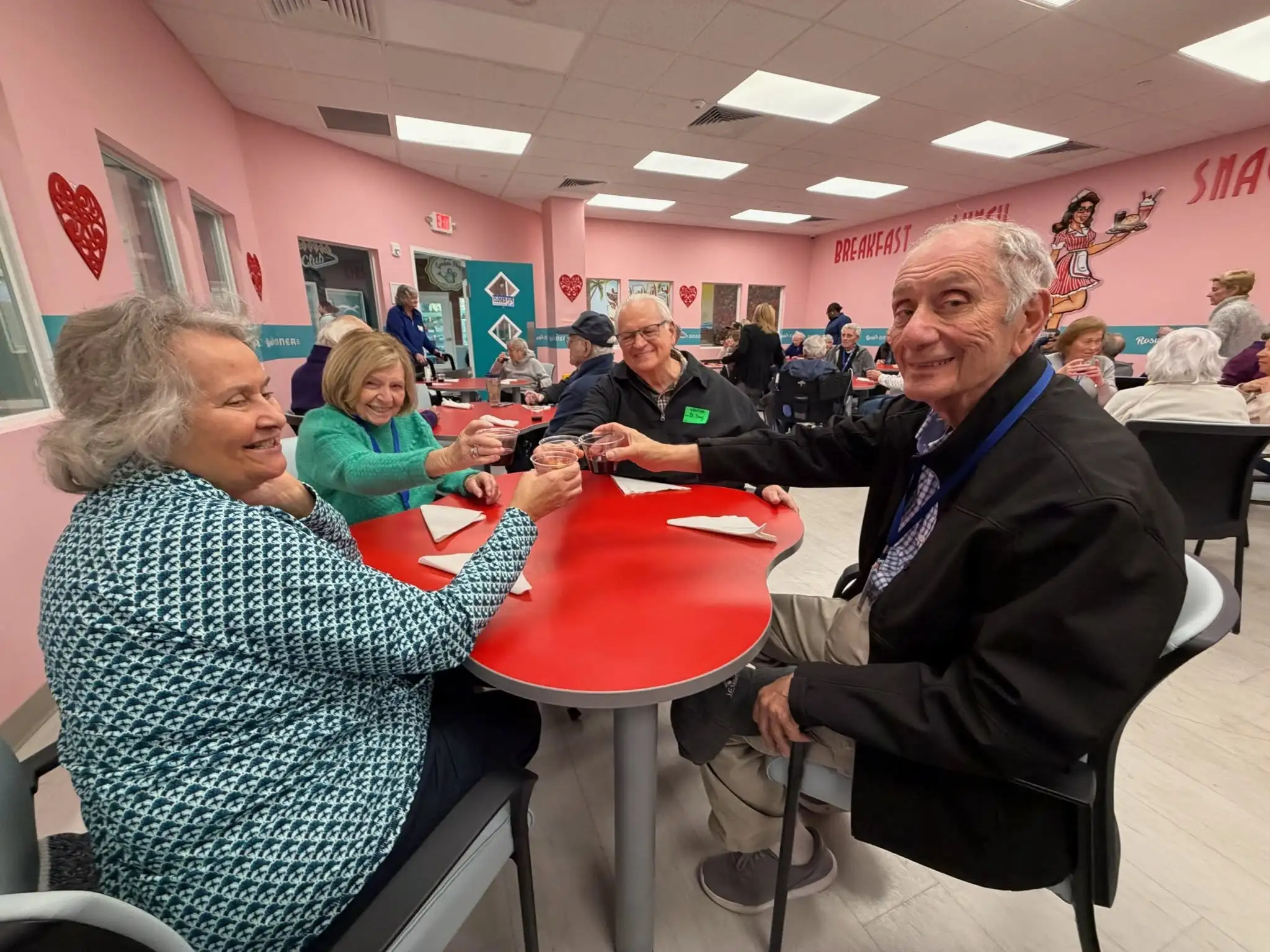 Five people are smiling and posing together inside a lively café in Bradenton, FL, characterized by modern decor, bright colors, and a friendly atmosphere.