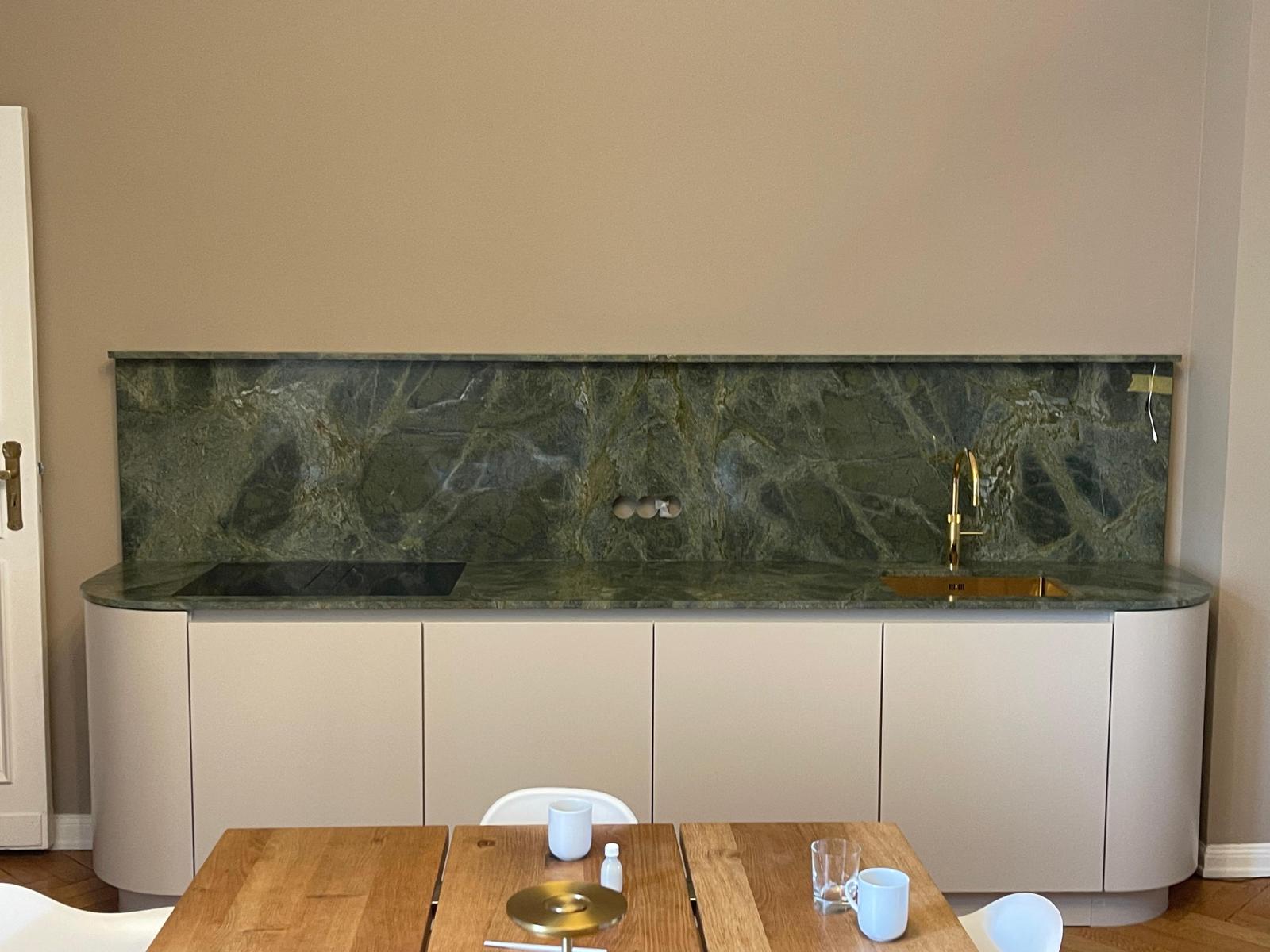 Dark kitchen with an illuminated backsplash.