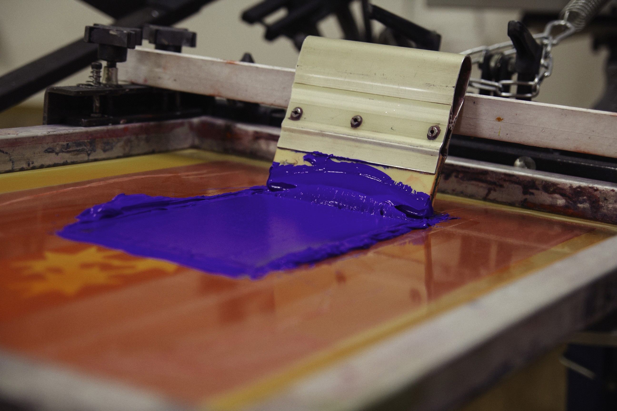 Ein Rakel mit blauer Farbe auf einem Siebdruckrahmen