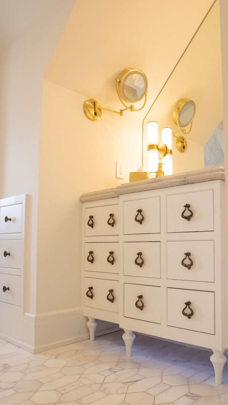 Image of Luxurious bathroom interior with marble floor, white dresser, and gold fixtures by KHD Homes.