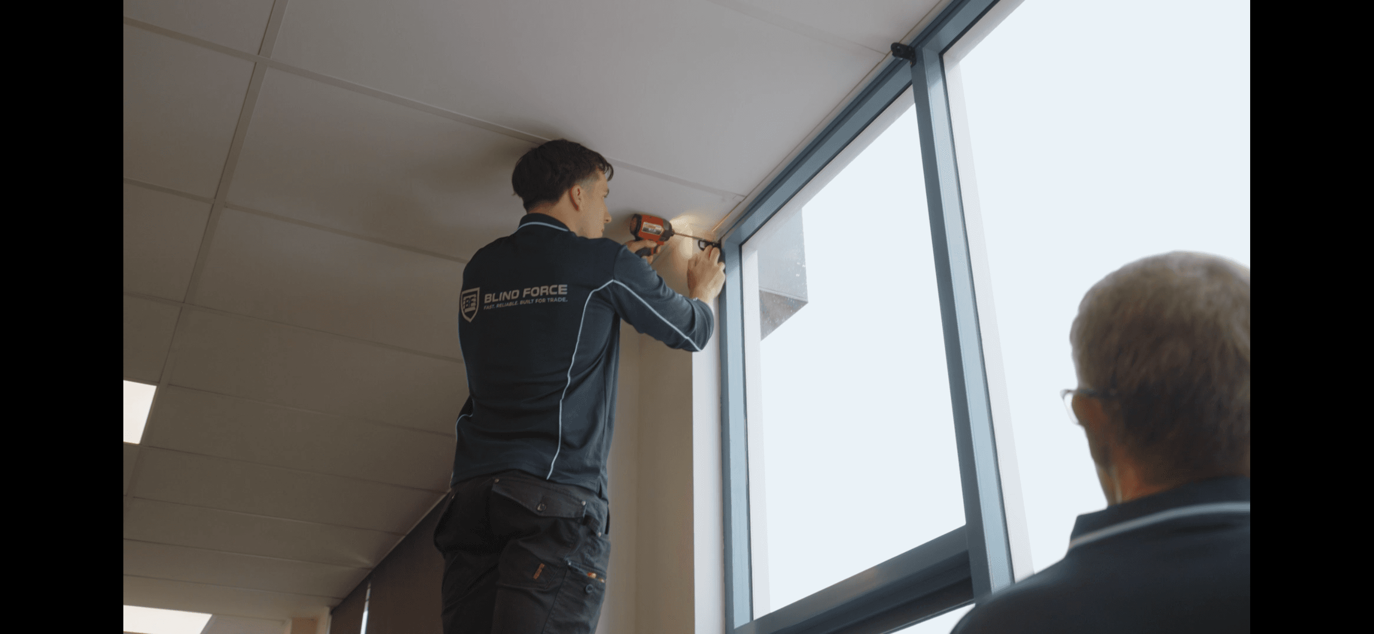 Blind installer fixing mounting brackets using Milwaukee Tool drill