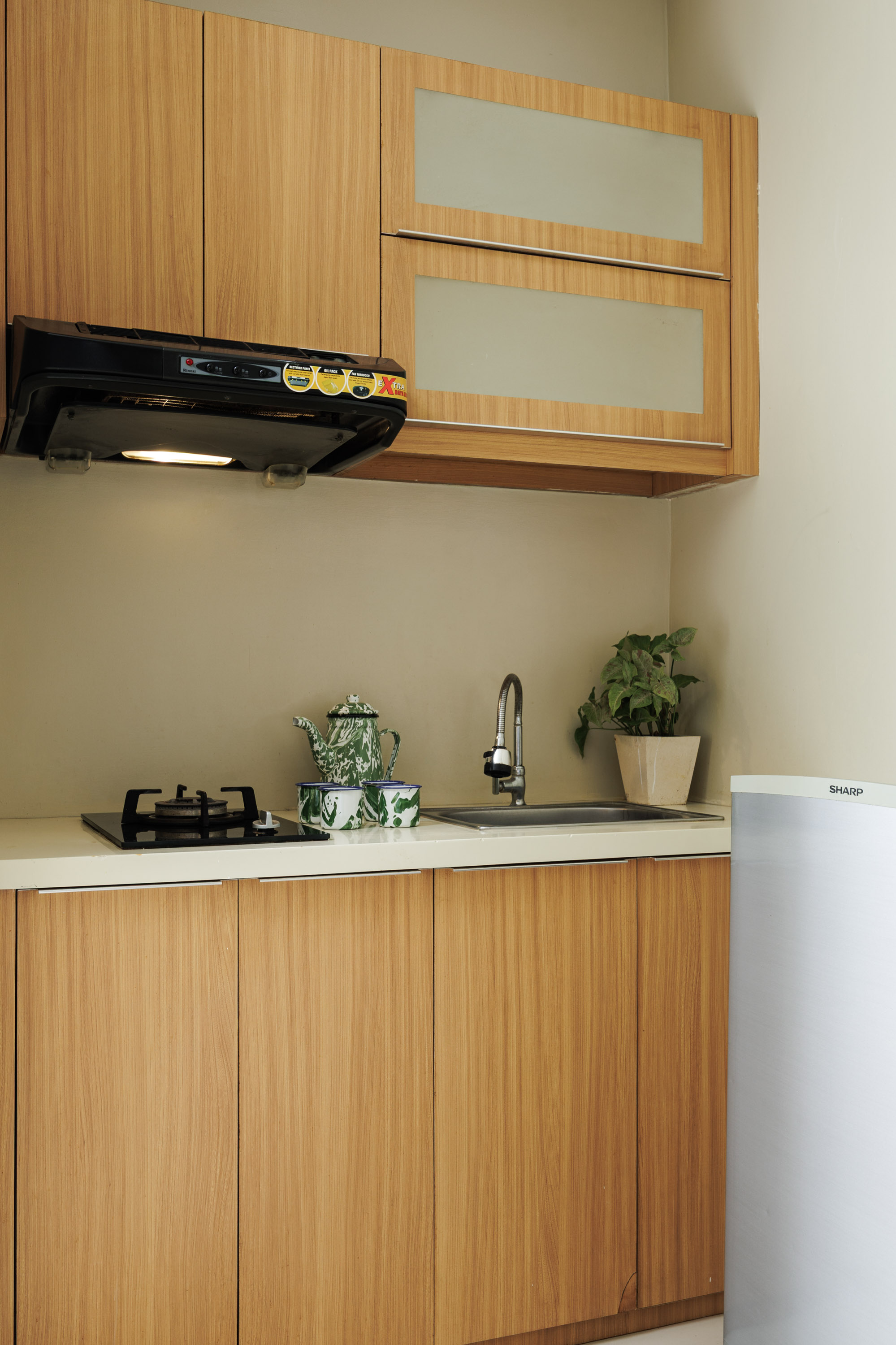 “Small kitchenette design with wooden cabinetry at Deva Bali Apartment”