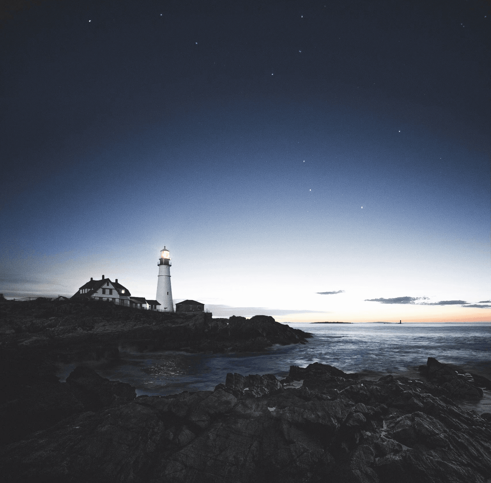 lighthouse beside house near the edge of stone island during day