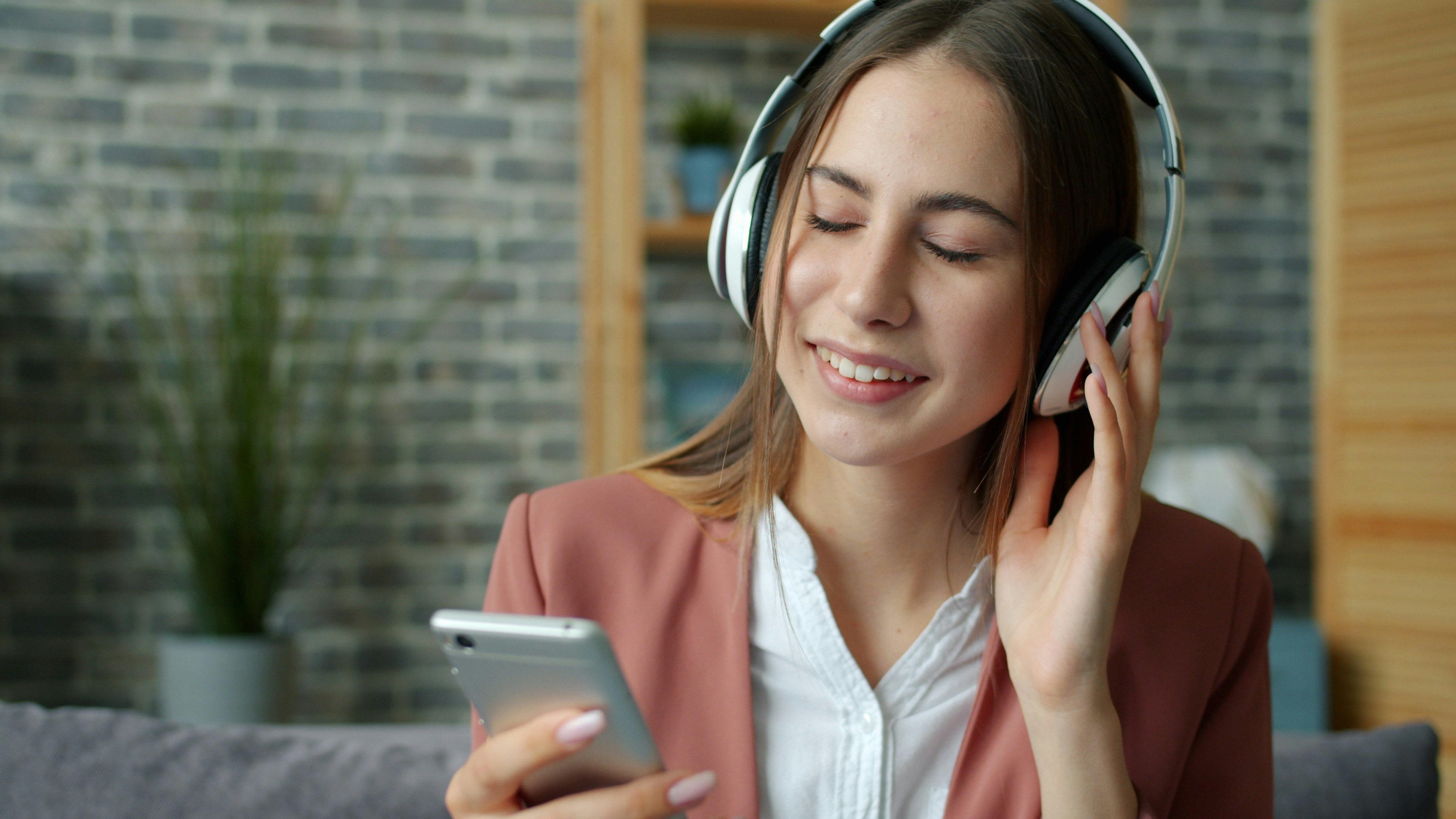 Young woman listening to music with headphones and smartphone.