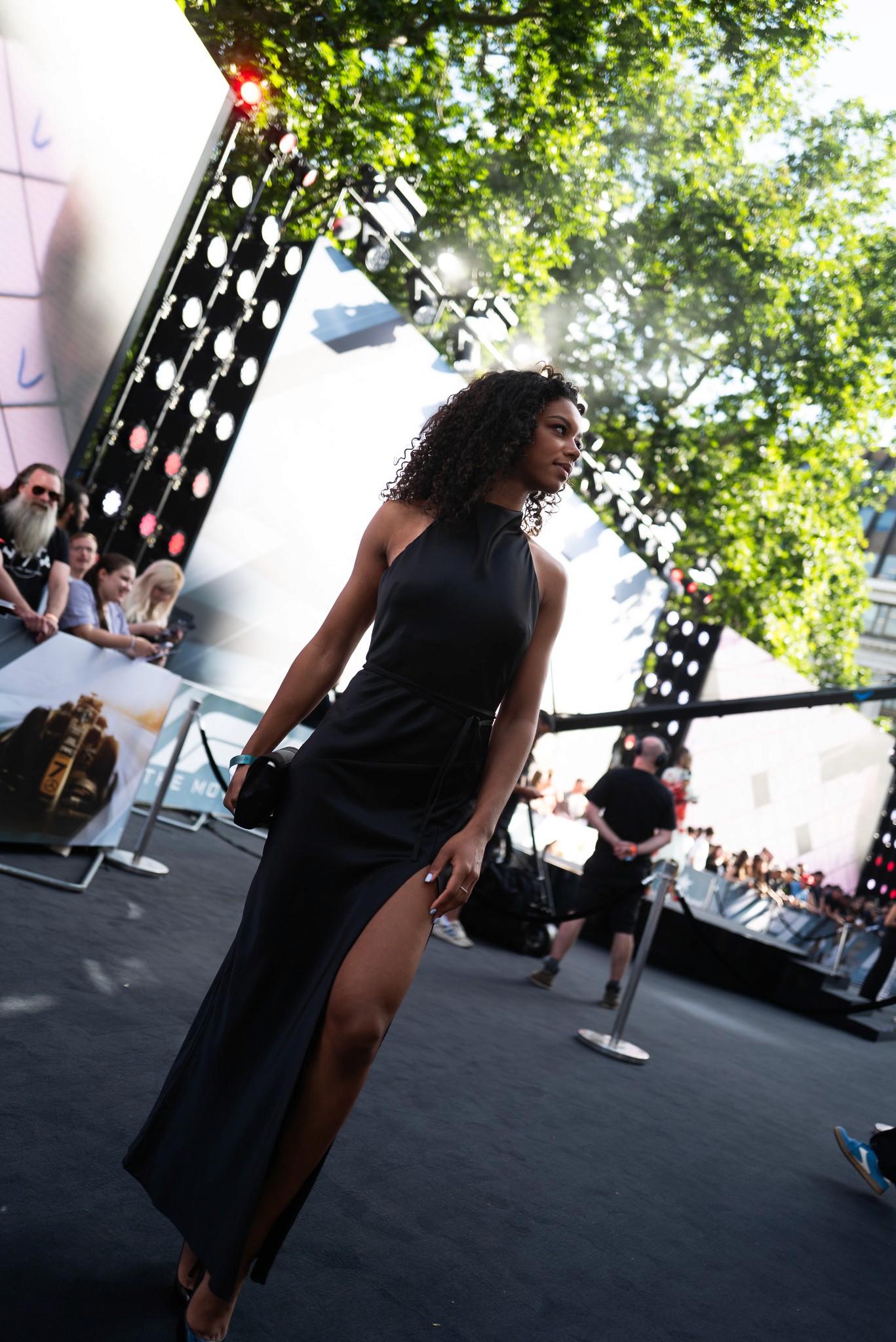 Bride sitting on ground against wall, groom standing nearby